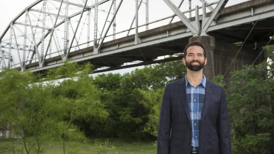 Dale Glover standing beneath a steel truss bridge in Austin.